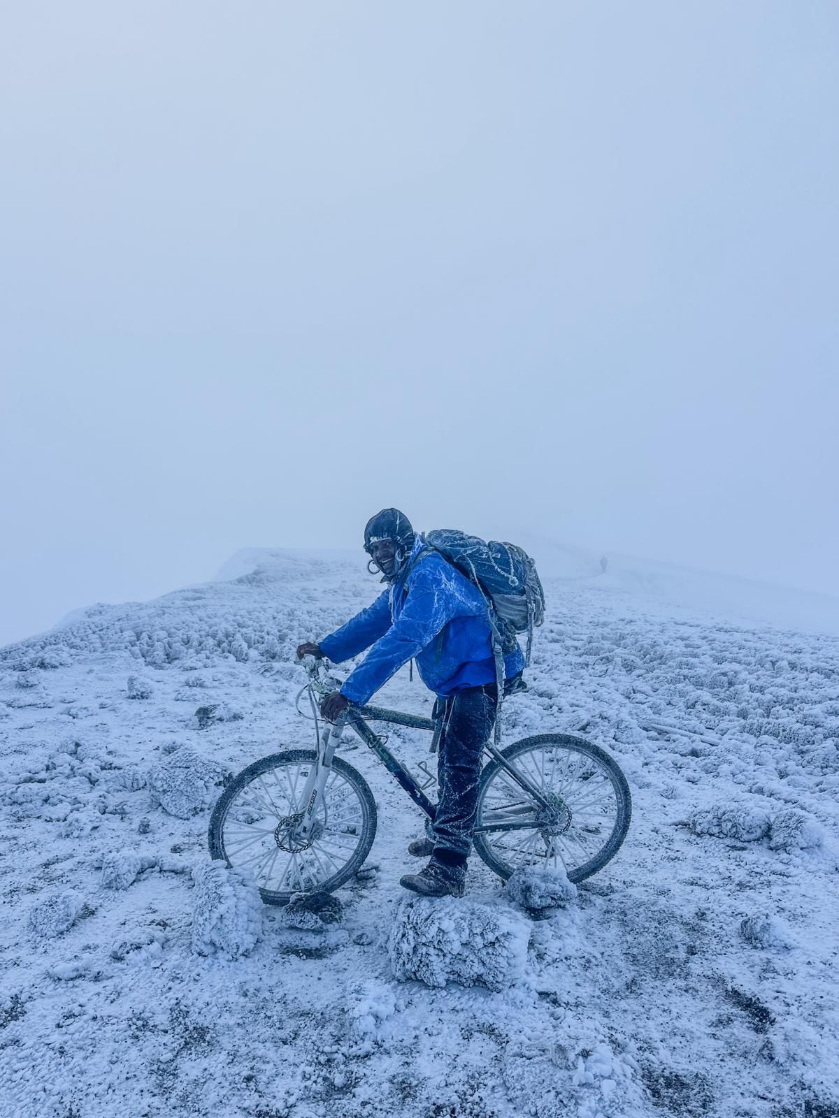 Ein Teammitglied mit Fahrrad auf dem verschneiten Kraterrand